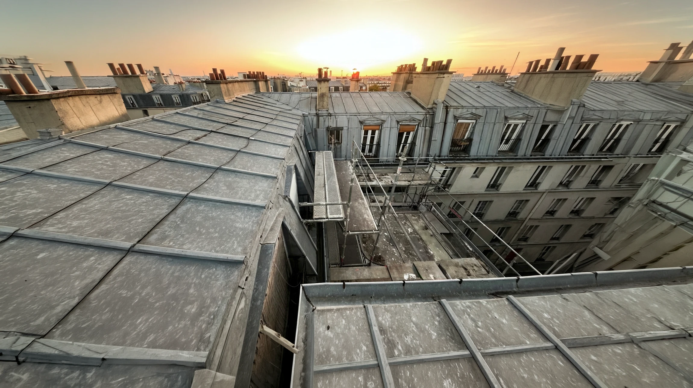 Extérieur, vue en contre-plongée d'une toiture pyramidale en ardoises avec charpente apparente et girouette décorative au sommet