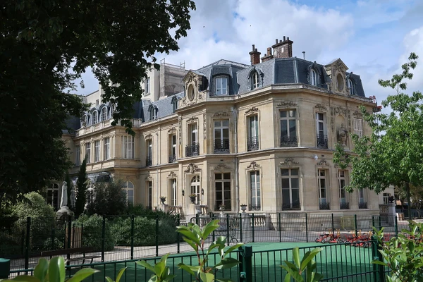 Photographie professionnelle d'un immeuble parisien classique de style Haussmannien situé à Boulogne-Billancourt, prise de face au niveau de la rue, montrant la façade élégante avec ses fenêtres typiques, ses balcons en fer forgé et sa toiture en ardoise/zinc visible en arrière-plan. L'image doit capturer l'architecture caractéristique des immeubles bourgeois de cette commune francilienne, illustrant le type de bâtiments sur lesquels ICR Couverture intervient.
